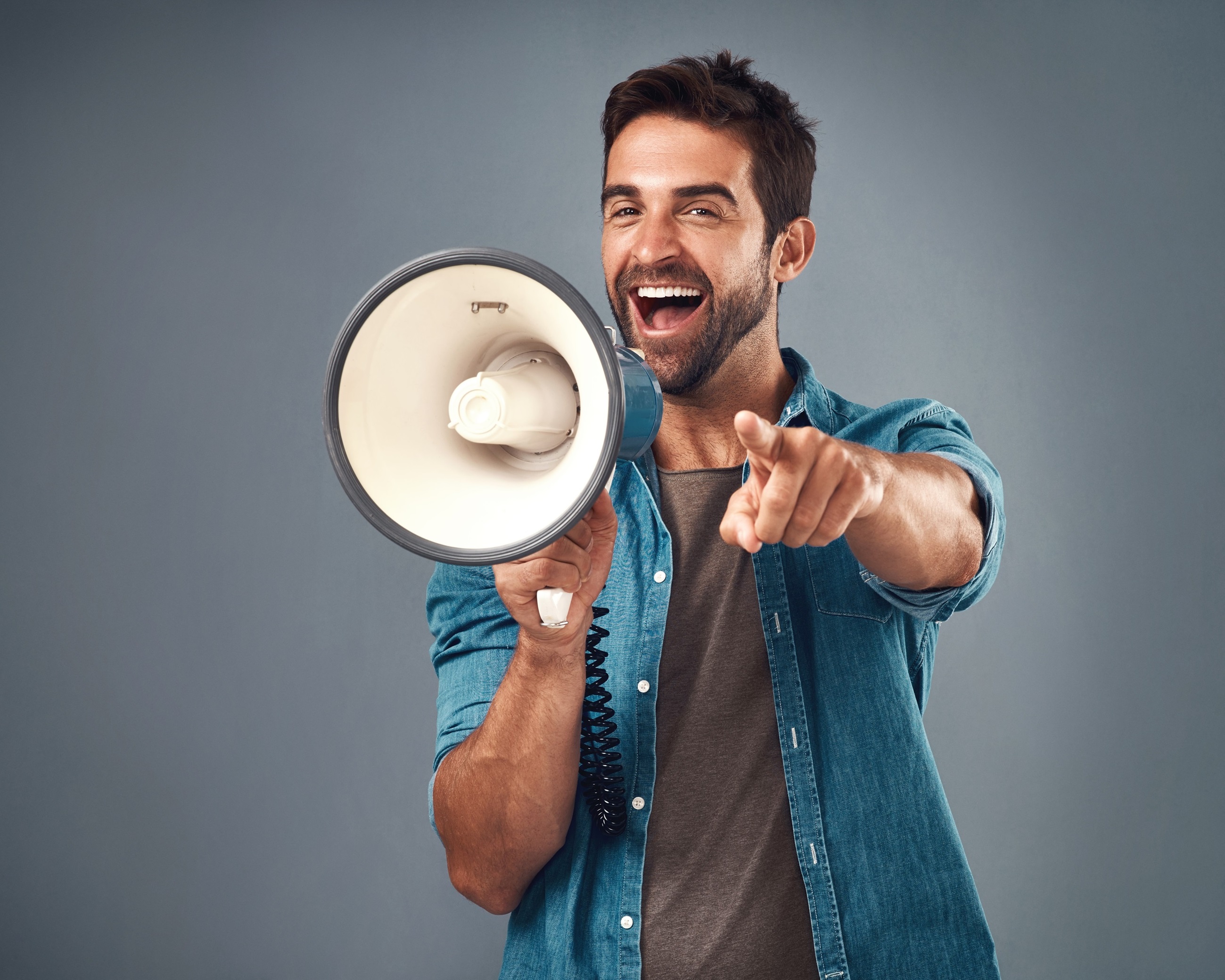 Happy, enthusiastic man making a congratulatory announcement into a megaphone.